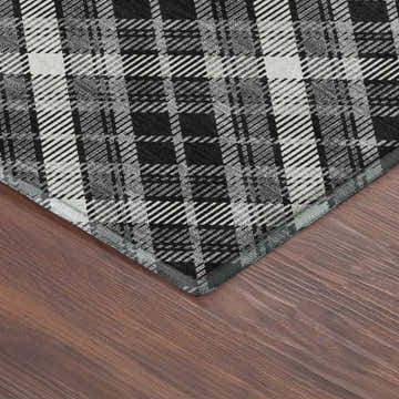 Close up of Dalyn Luxury Soft Essentials Black Washable Area Rug with a black and white plaid pattern on a wood floor.
