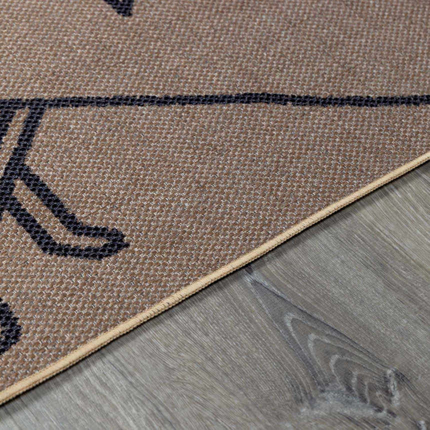 Close-up of the camel Hamid Washable Jutely Rug showing jute texture and dark brown pattern on gray wood flooring. Pile