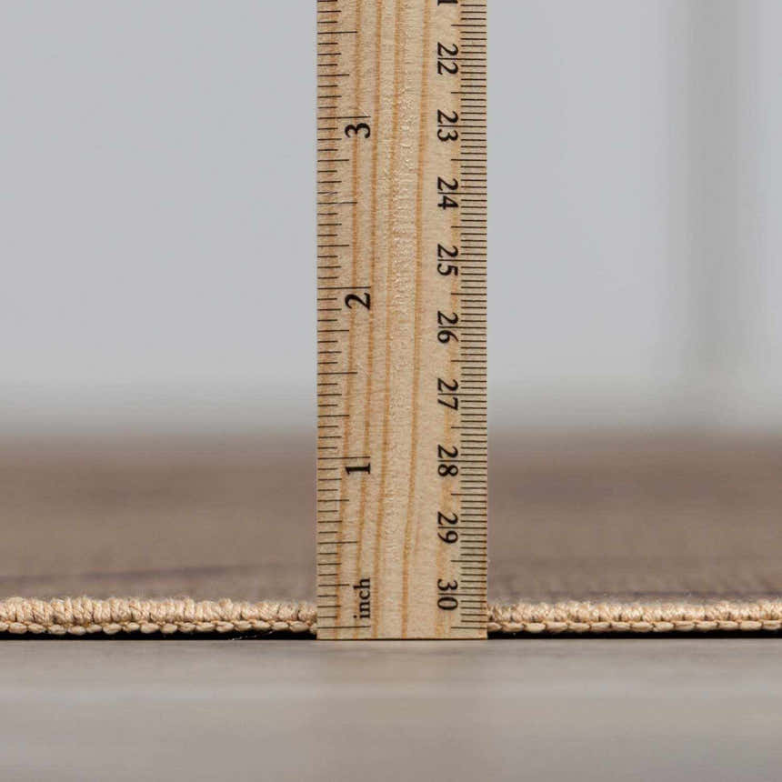 Close-up of the Hamid Washable Jutely Rug showing the pile height with a ruler, revealing its low profile. Pile