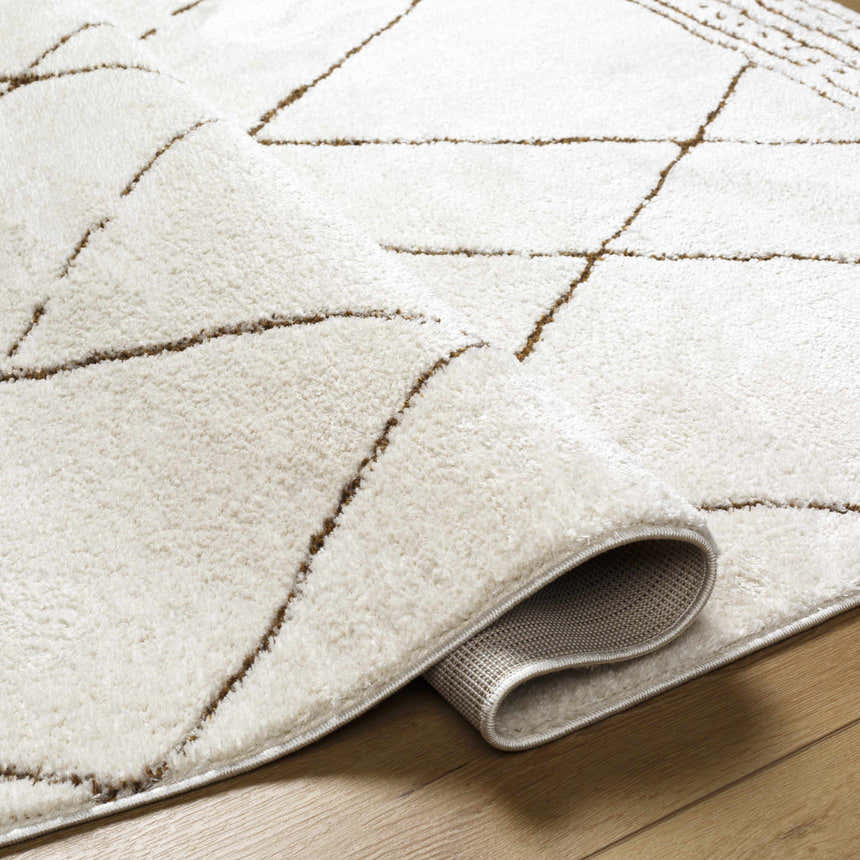 Close-up of the Keone Area Rug: beige polyester rug with a brown geometric line pattern and a soft, plush texture. Fold