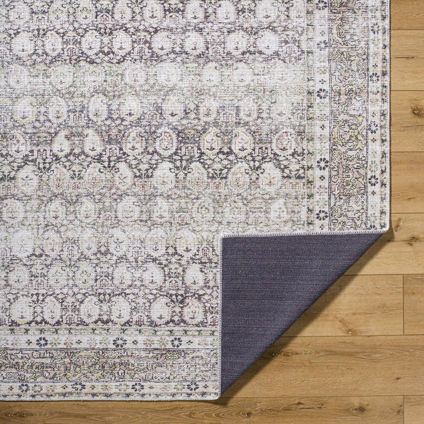 Close-up of the Mabyn Area Rug showing its traditional design, neutral colors, and machine-woven texture on a wood floor. Fold