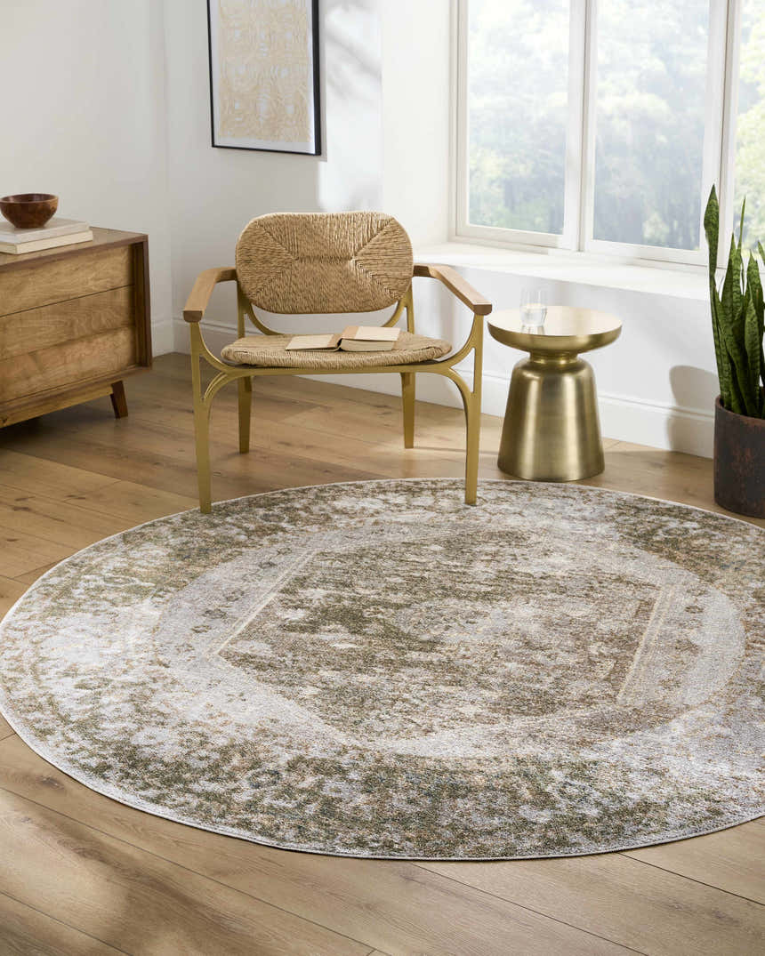 Living room scene with a round Gael Boutique Washable Rug in light blue, olive, and tan under a chair and side table. Roomscene-Round