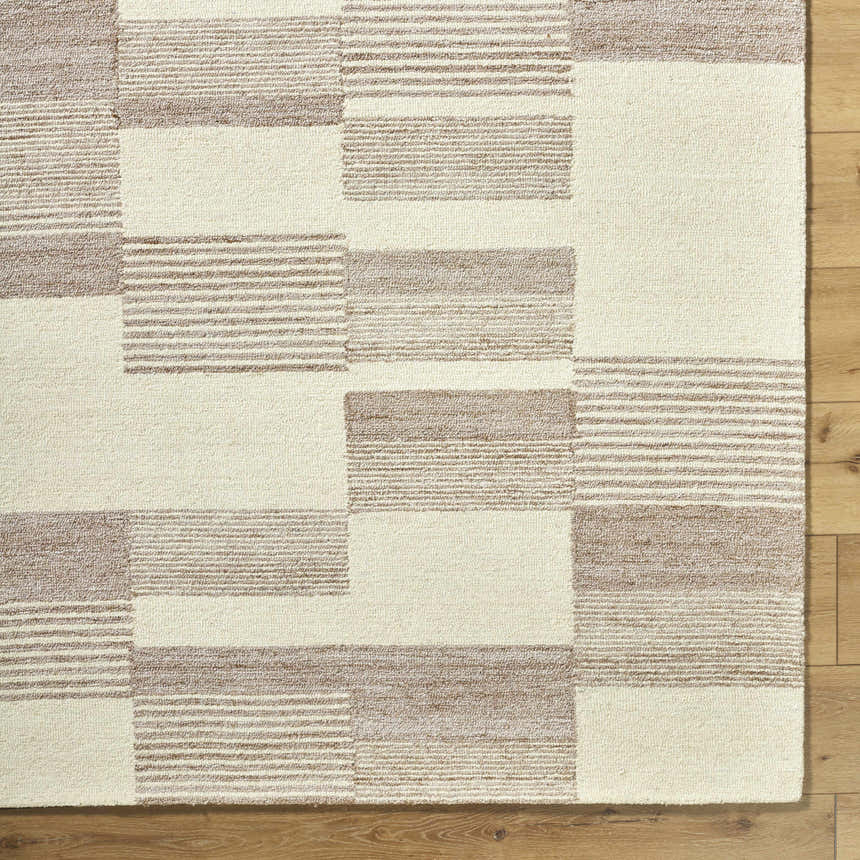 Close-up of the Eyad Area Rug, showcasing its beige and brown geometric block and striped pattern. Hand-tufted texture detail. Corner