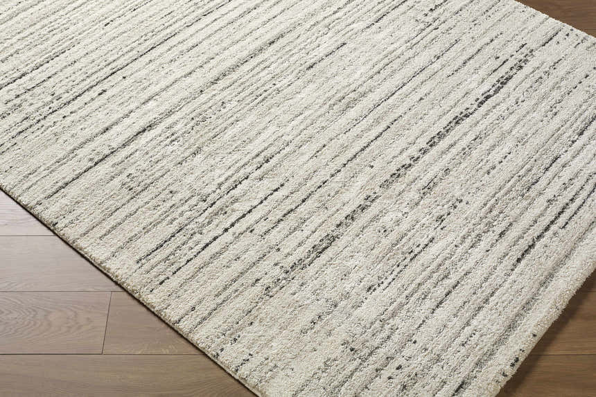 Close-up of the Salus Luxe Rug. Beige and cream rug with a contemporary black striped pattern. Corner