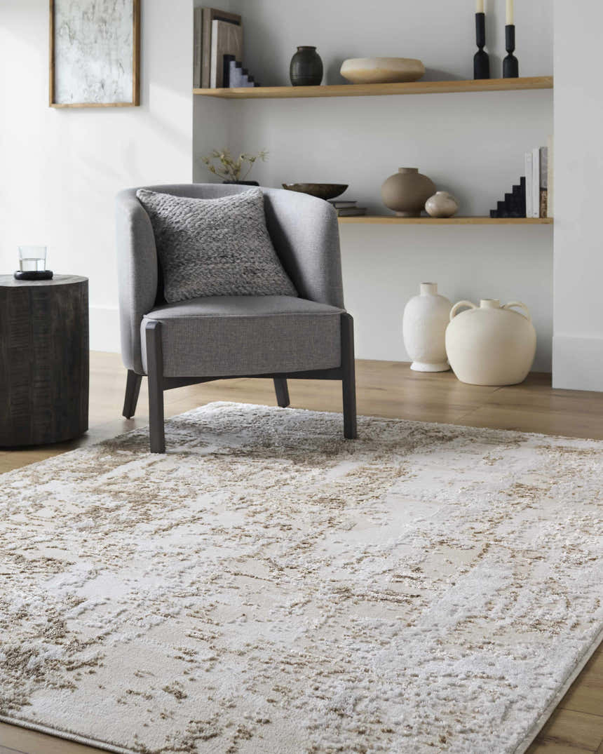 Living room scene with a beige and cream Junko Area Rug, gray chair, wood side table, and decorative shelves. Roomscene-Rectangle