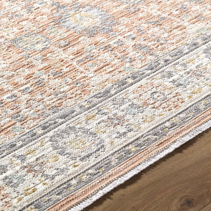 Close-up of the Adilet Dark Pink Washable Area Rug. Features a traditional, farmhouse pattern with pink, gray, and cream tones. Texture