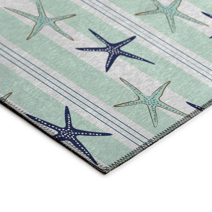 Close-up of Dalyn Seabreeze SZ12 Mist Washable Area Rug. Coastal style with blue starfish on a striped muted sage and off-white background.