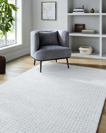 Living room scene with light blue Andreas Handmade Vivir x LIVABLISS rug, gray chair, and white shelving. Roomscene-Rectangle