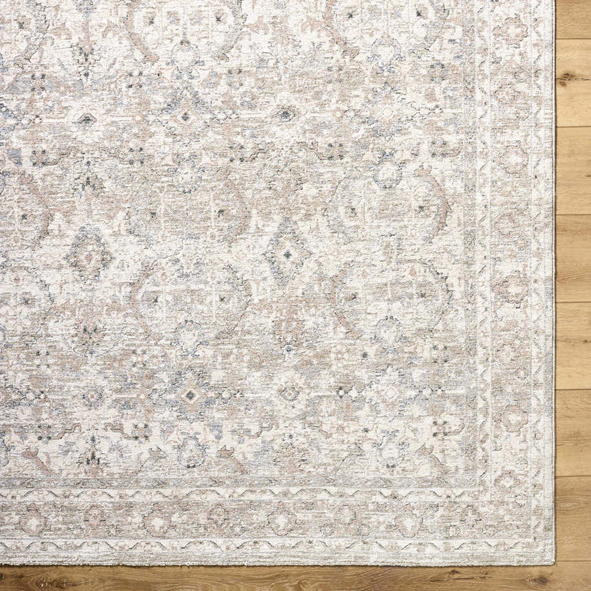 Close-up of the Tyren Area Rug featuring a traditional cream, tan, and slate blue floral pattern on a textured polyester weave. Corner