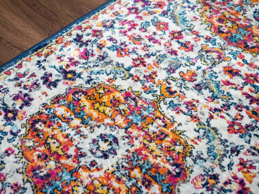 Close-up of the Tigril Blue & Orange 2304 Area Rug. Features a bohemian floral pattern in ivory, navy, red, and orange. Texture