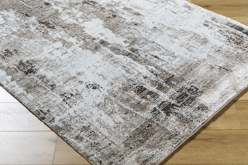 Close-up of the Taszi Luxe Thick Area Rug. Contemporary style rug in black, ivory, peach, and tan on hardwood floor. Corner