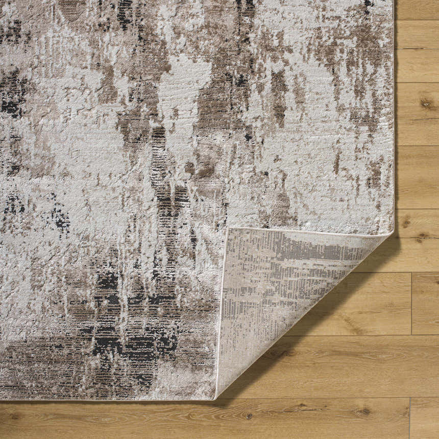 Close-up of Taszi Luxe Thick Area Rug showing ivory, tan, and black abstract pattern and machine-woven construction. Fold
