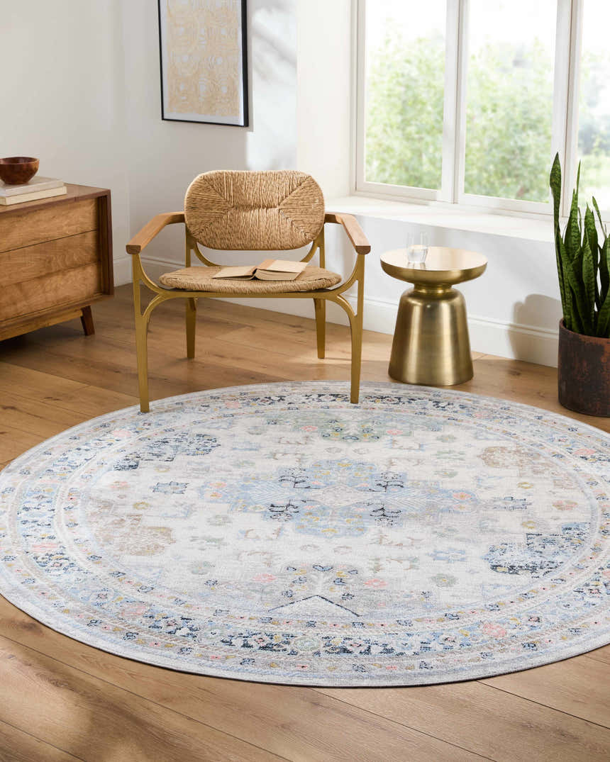 Living room scene with round Tana Washable Area Rug in Arctic Stone, woven chair, wood dresser, and gold side table. Roomscene-Round