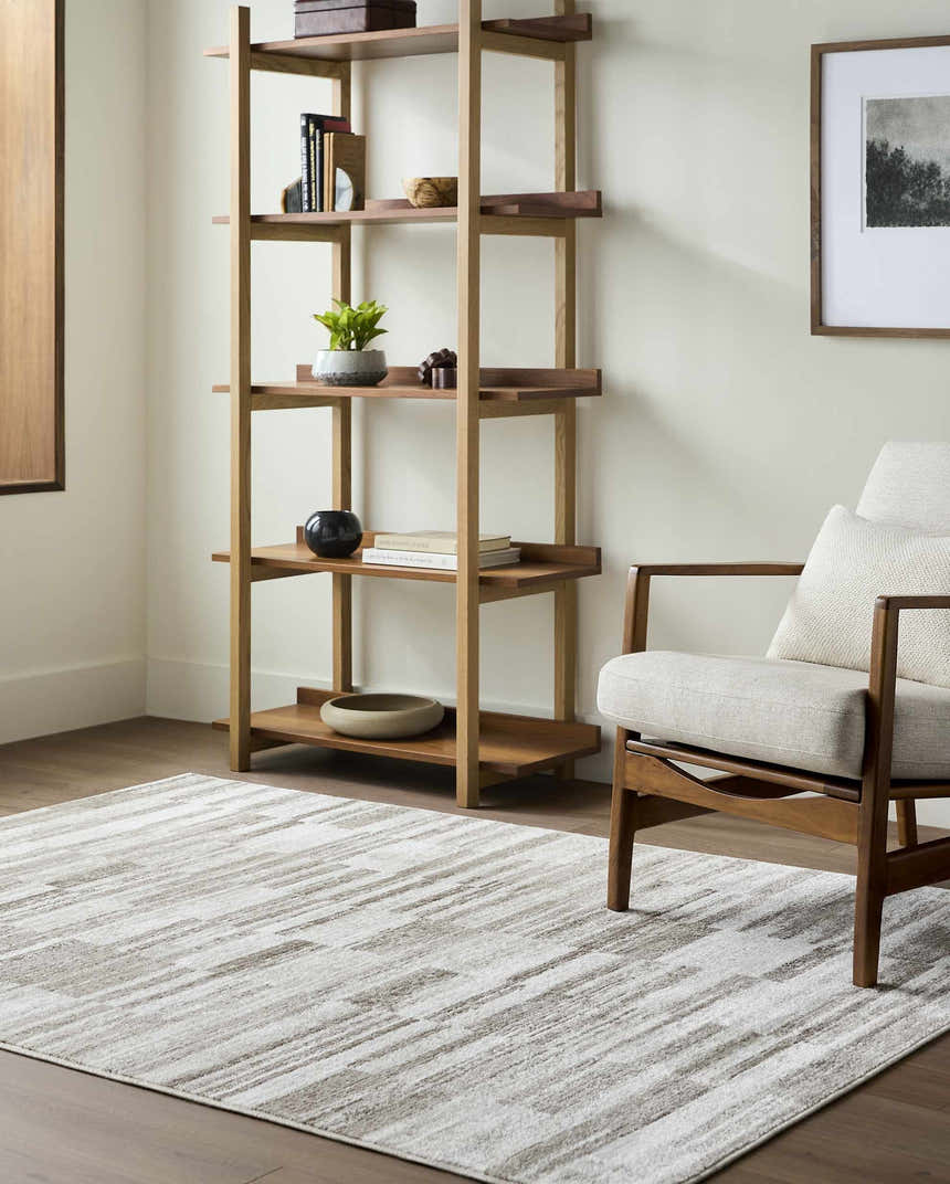 Living room scene with a Tehya Beige Area Rug, wood bookshelf, and mid-century modern chair. Roomscene-Rectangle