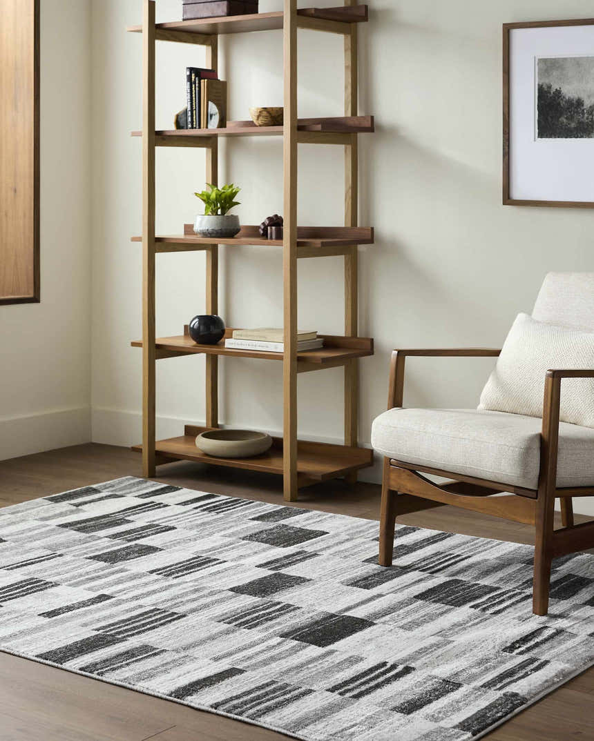 Living room scene with a Tehya Gray Area Rug, wood bookshelf, and mid-century modern chair. Roomscene-Rectangle