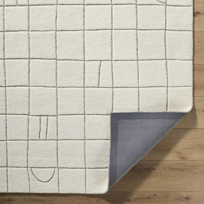 Close-up of the Tuuka Beige Area Rug showing its wool texture, geometric grid pattern, and gray backing. Fold