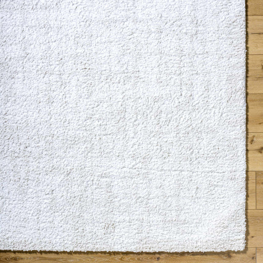 Close-up of the white Troya Area Rug showing its shag texture on a wood floor. Corner
