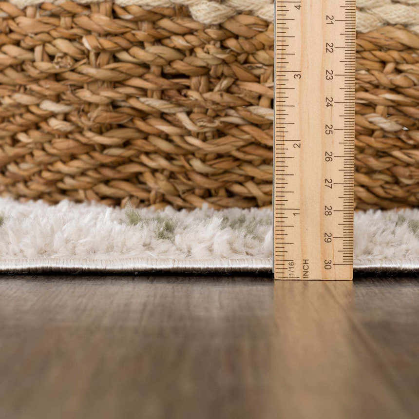 Close-up of the Azriel Green Washable Area Rug showing pile height with a ruler and a woven basket for texture comparison. Pile
