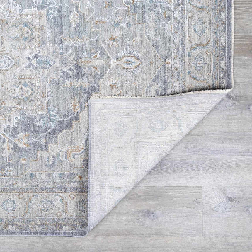 Close-up of the Ulubey Distressed Gray Thick Luxe Area Rug showing its traditional pattern and colors like gray, beige, and blue. Fold