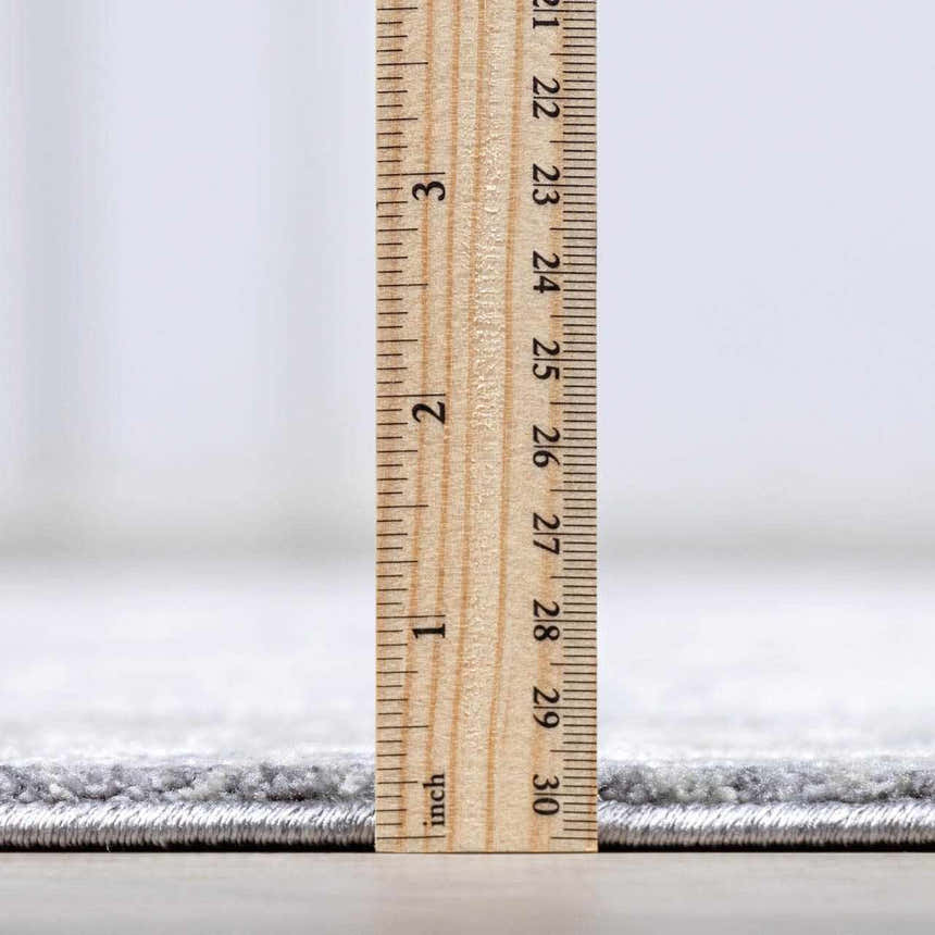 Close-up of the thick pile height of the Ulubey Distressed Gray Luxe Area Rug, measured with a ruler. Pile