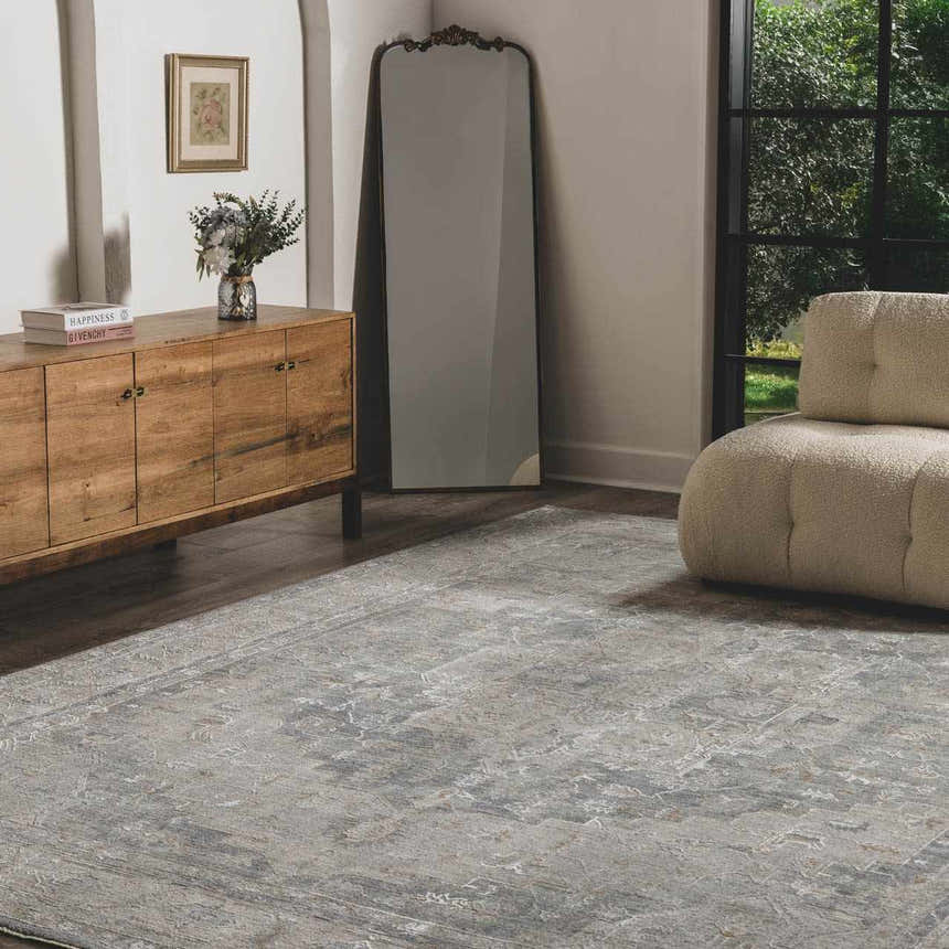 Living room scene with Ulubey Distressed Gray Thick Luxe Area Rug, wood cabinet, mirror, and cream boucle chair. Roomscene-Rectangle