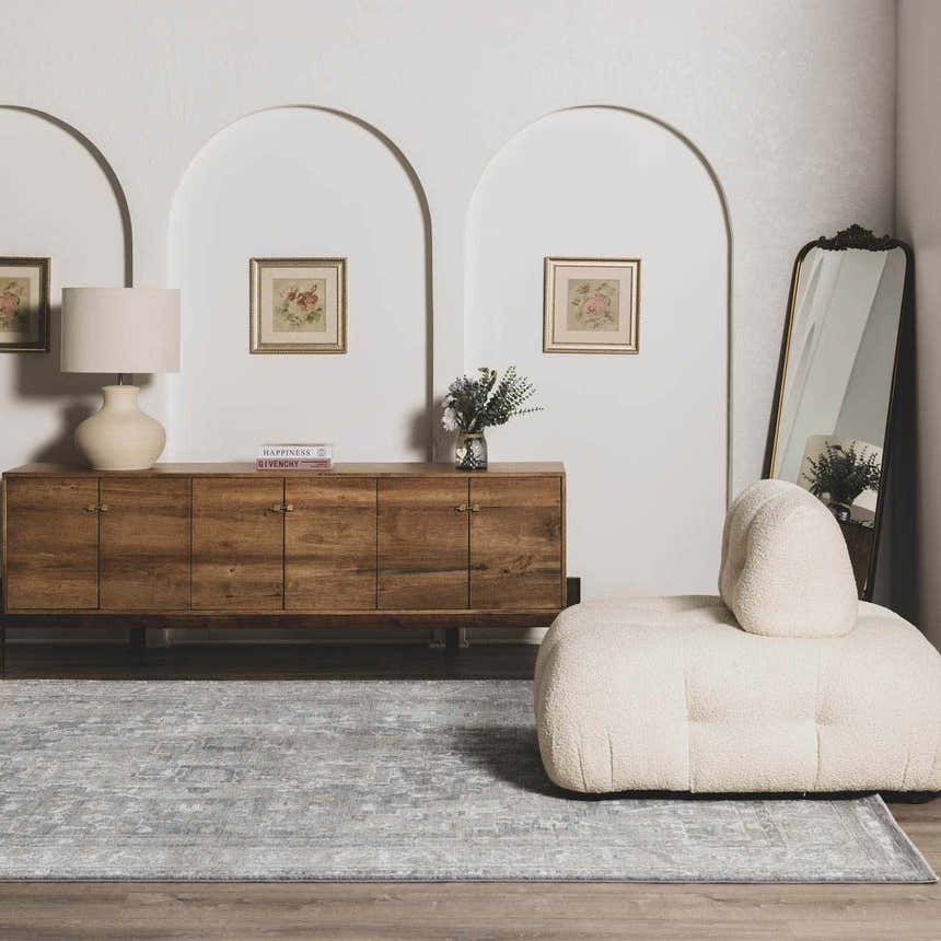 Living room scene with a gray Ulubey Distressed rug, wood cabinet, cream chair, arched doorways, and vintage decor. Roomscene-Rectangle