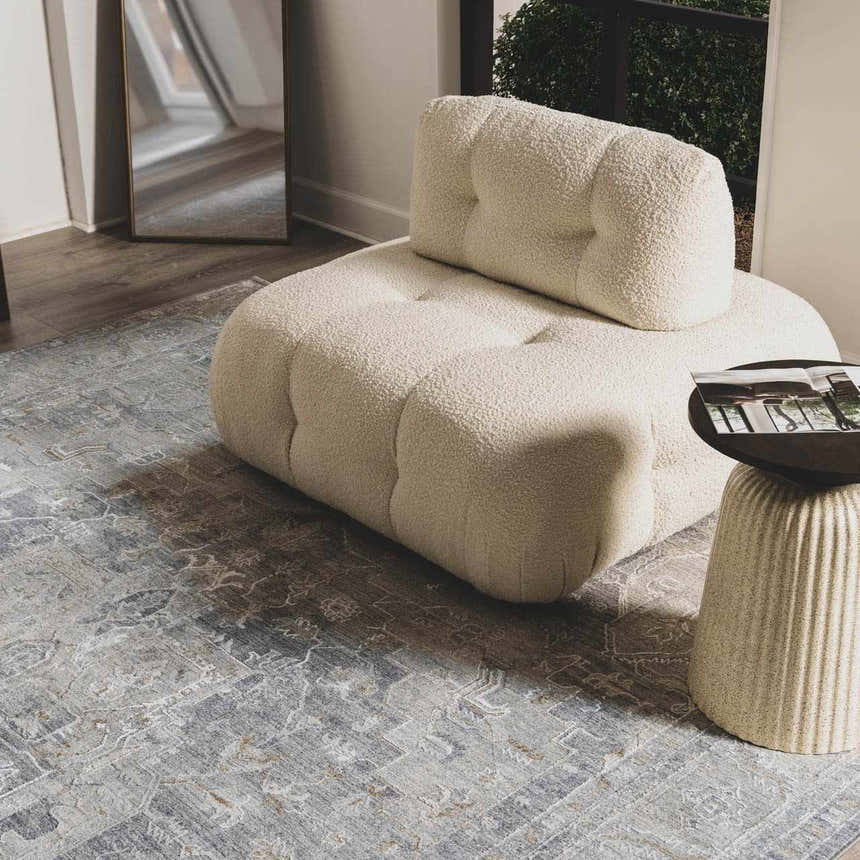 Living room scene with a cream boucle chair on the Ulubey Distressed Gray Thick Luxe Area Rug. Styleshot