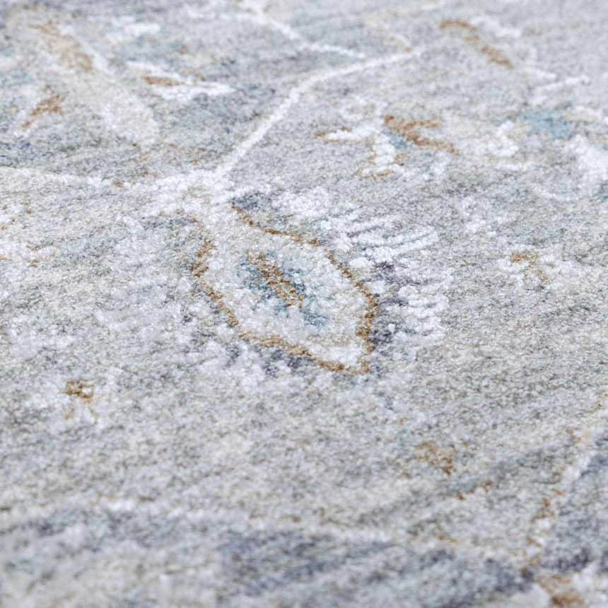 Close-up of the Ulubey Distressed Gray Thick Luxe Area Rug, showing its texture and traditional pattern. Colors: gray, beige, blue. Texture