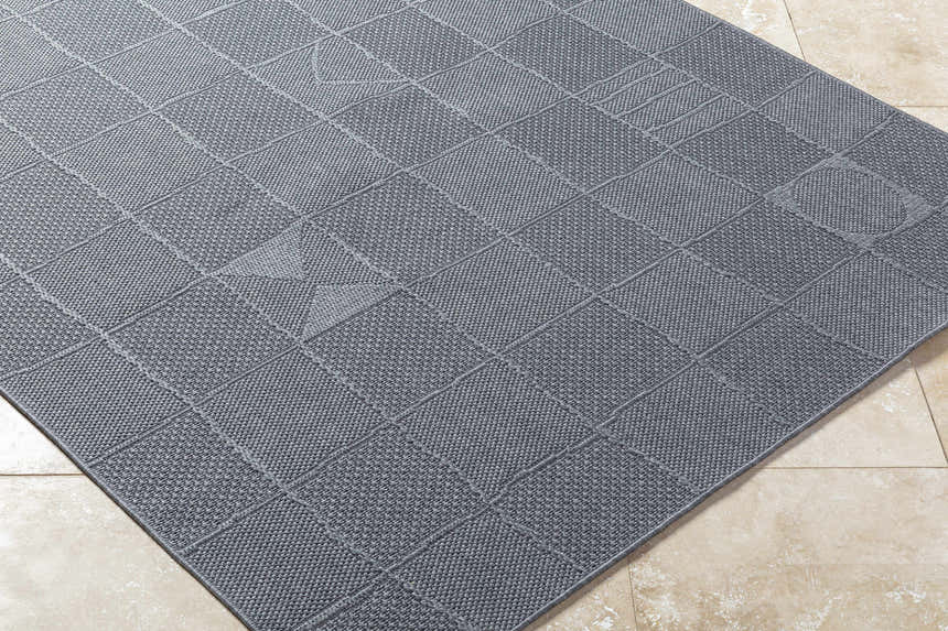 Close-up of the Veras Charcoal Area Rug. Gray rug with a contemporary square pattern and textured weave. Corner