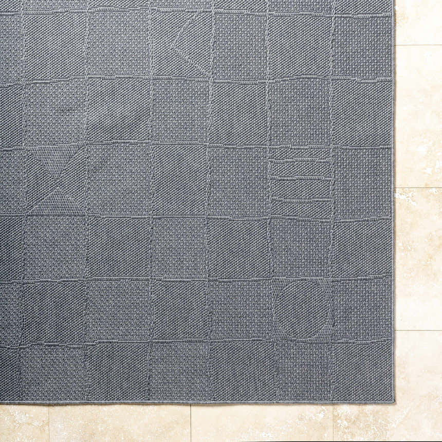 Close up of the Veras Charcoal Area Rug showing the woven texture and geometric block pattern. Corner