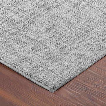 Close-up of the textured Dalyn Luxury Voyage VY1 Silver Washable Area Rug on a wood floor.