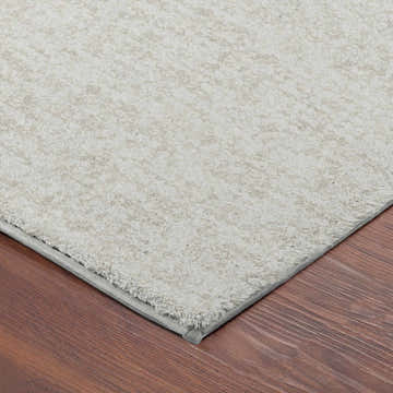 Close-up of the textured Dalyn Luxury Voyage VY2 Ivory Washable Area Rug on a wood floor.