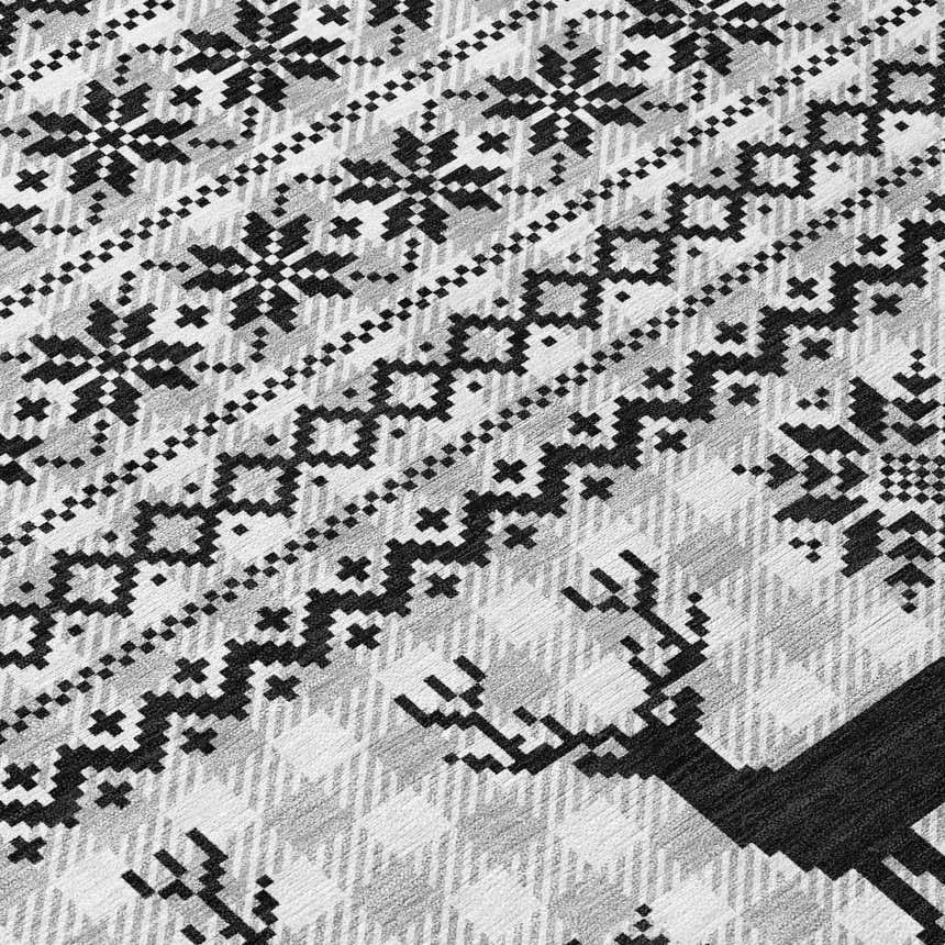 Close-up of the Dalyn Wonderland WN28 Silver Washable Area Rug featuring a black and gray snowflake and reindeer pattern.