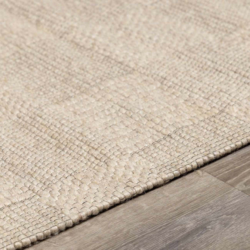 Close-up of the hand woven Wolseth Area Rug in off white and gray, showing texture and detail on wood floor. Pile