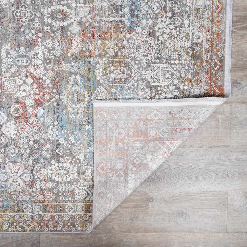 Close-up of the Witheridge Area Rug showing its gray, blue, pink, and red traditional pattern and machine woven construction. Fold