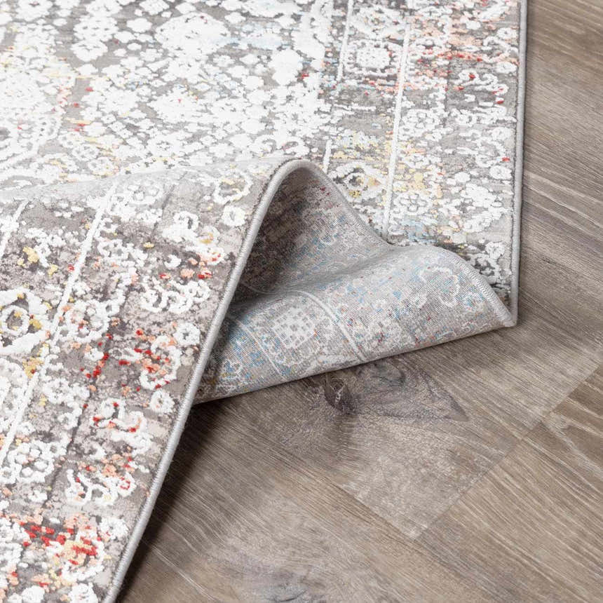 Close-up of the Witheridge Area Rug showing its gray, white, red, and blue traditional pattern and machine-woven construction. Fold