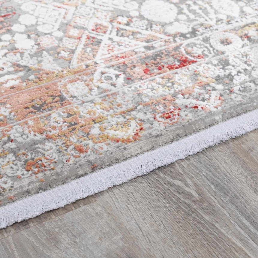 Close-up of the Witheridge Area Rug showing a gray, dusty pink, and red traditional pattern with fringe. Pile