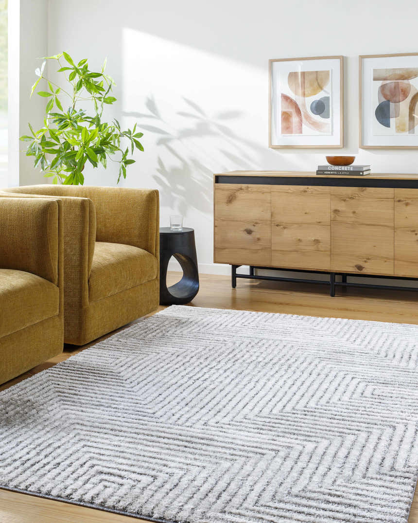 Living room scene with yellow armchairs and the Aerith Shag Area Rug in light silver with a geometric pattern. Roomscene-Rectangle