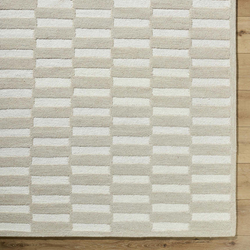 Close up of the Uther Area Rug, a hand-tufted wool rug with a beige and ivory geometric pattern. Corner