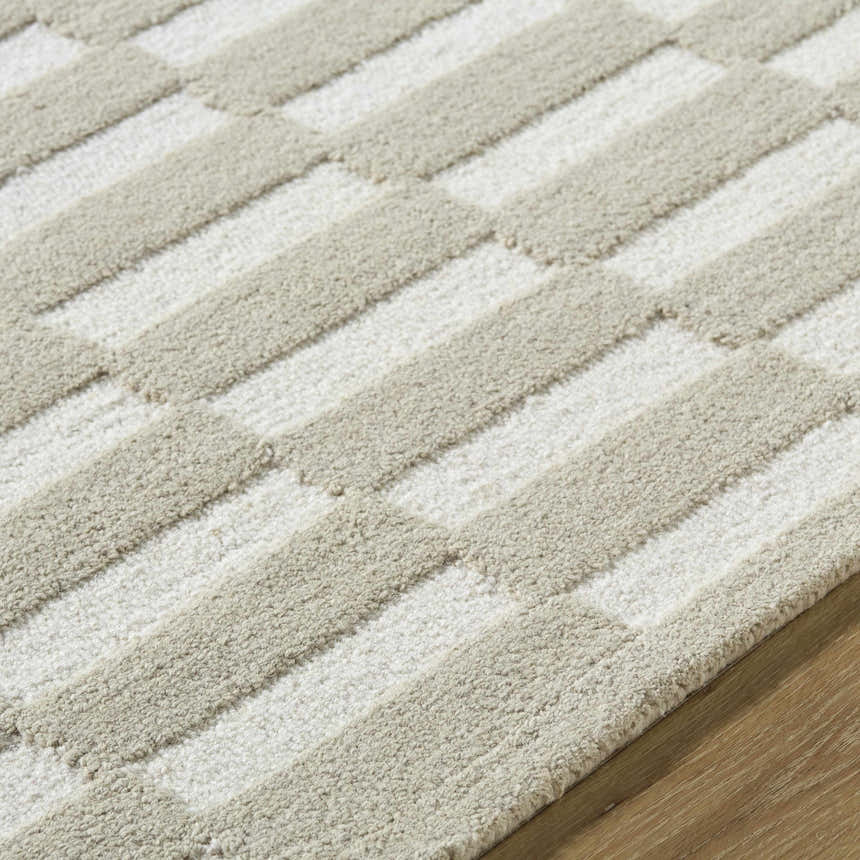Close-up of the Uther Area Rug, a hand-tufted wool rug with a beige and ivory geometric pattern. Texture