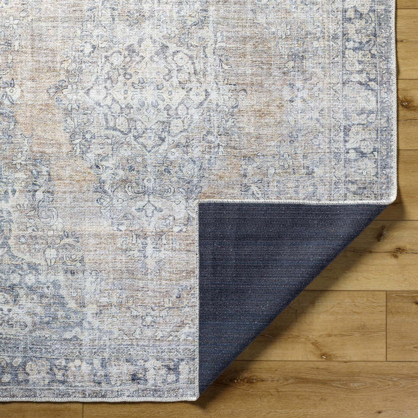 Close-up of the Yachi Washable Area Rug showing its farmhouse style, traditional pattern, and gray, silver, and prairie dust colors. Fold