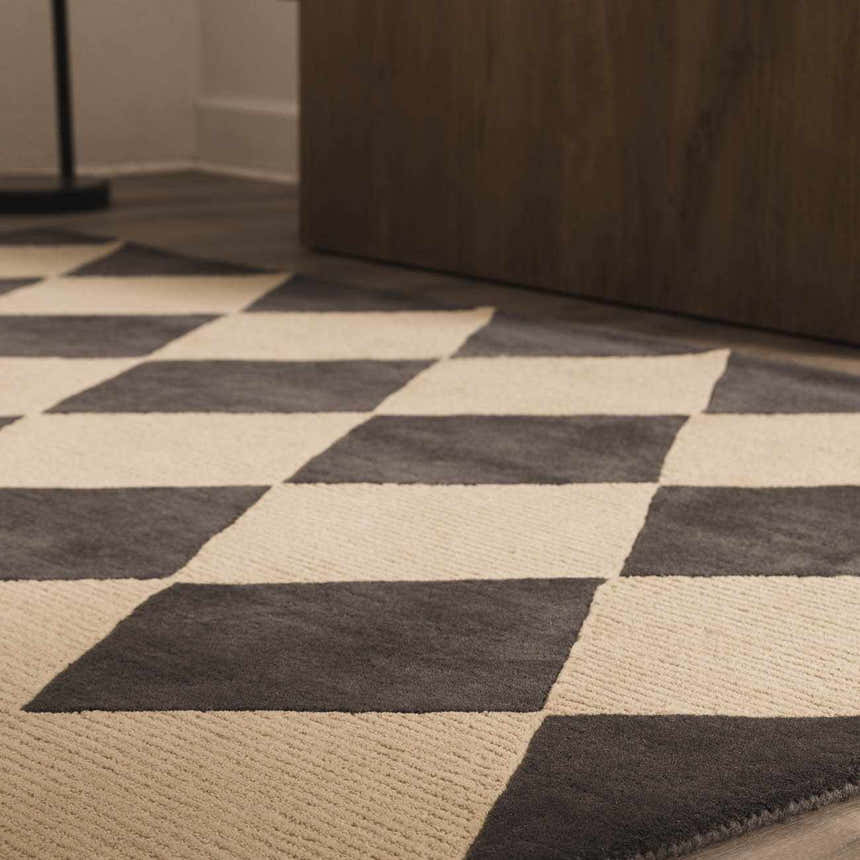 Close up of the Aradia Charcoal Area Rug, a hand-tufted wool rug with a bold charcoal and cream diamond pattern. Styleshot