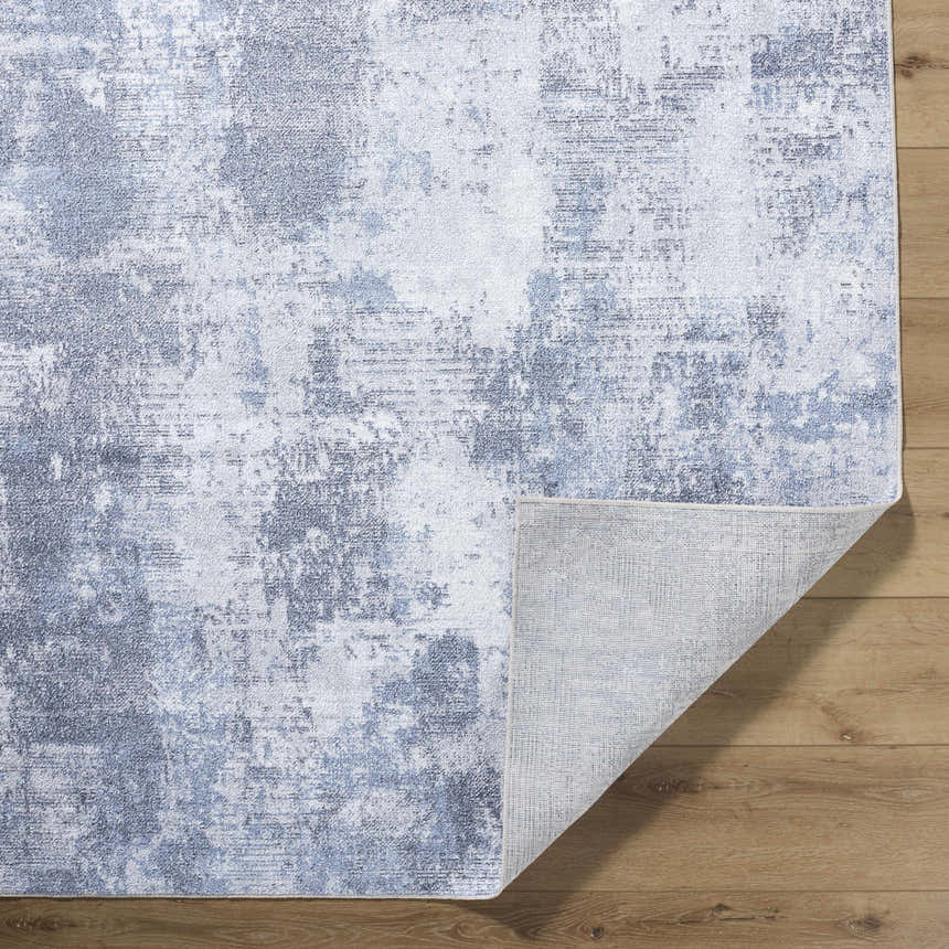 Close-up of Anitra Off White Washable Area Rug showing navy and off-white abstract pattern and rug backing. Fold