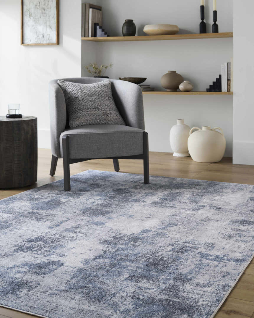 Living room scene with a gray chair on the Anitra Off White Washable Area Rug, creating a contemporary, neutral space. Roomscene-Rectangle
