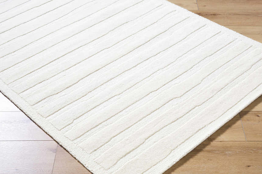 Close-up of the hand-tufted Zerah White Wool Area Rug, featuring a light silver and off-white striped design and soft texture. Corner