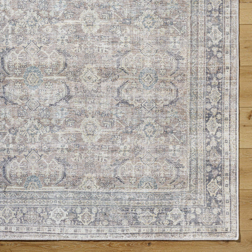 Close-up of the Zahar Washable Area Rug. Light silver, silver gray, and warm gray traditional pattern on wood floor. Corner