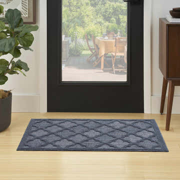 Entryway scene with navy blue Nourison Easy Care runner rug, wood floors, black door, and view to outdoor patio.