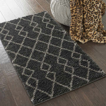 Nourison Martil Charcoal Moroccan shag rug on wood floor with gray pouf and leopard print throw.