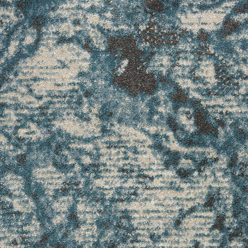 Close-up of Nourison Maxell Ivory/Teal rug. Abstract pattern with teal, ivory, and chestnut colors. Soft, textured polyester.