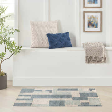 Modern living room scene with blue and ivory Nourison Astra area rug and neutral decor.
